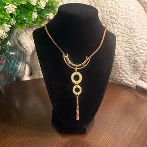 Gold tone pendant on brown knotted cord